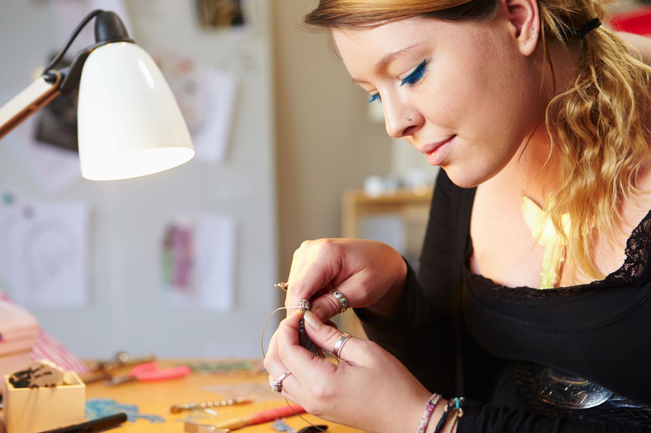 young-woman-making-jewelry-at-home-PT474FM.jpg